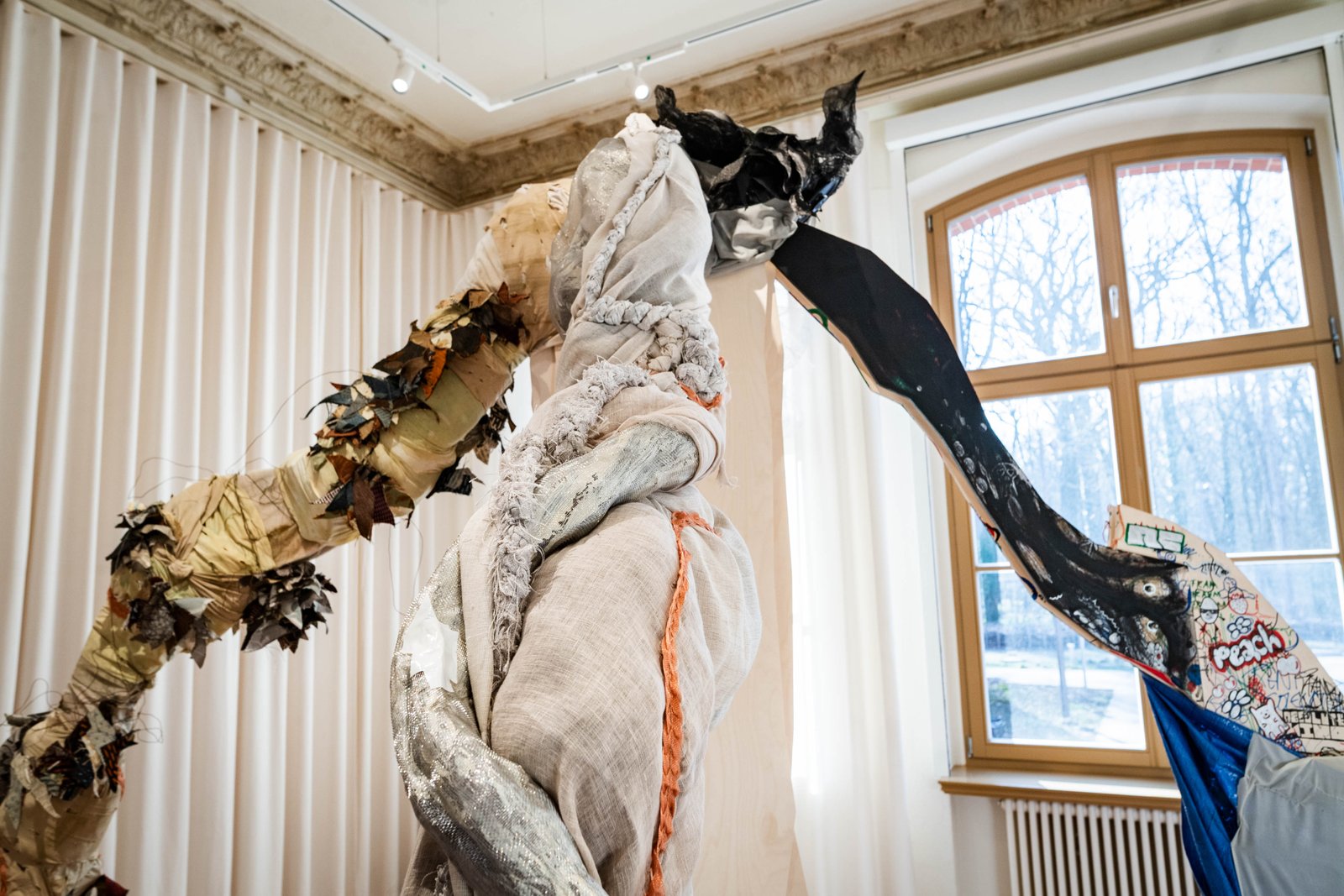 The sculpture arching past a window in a gallery room