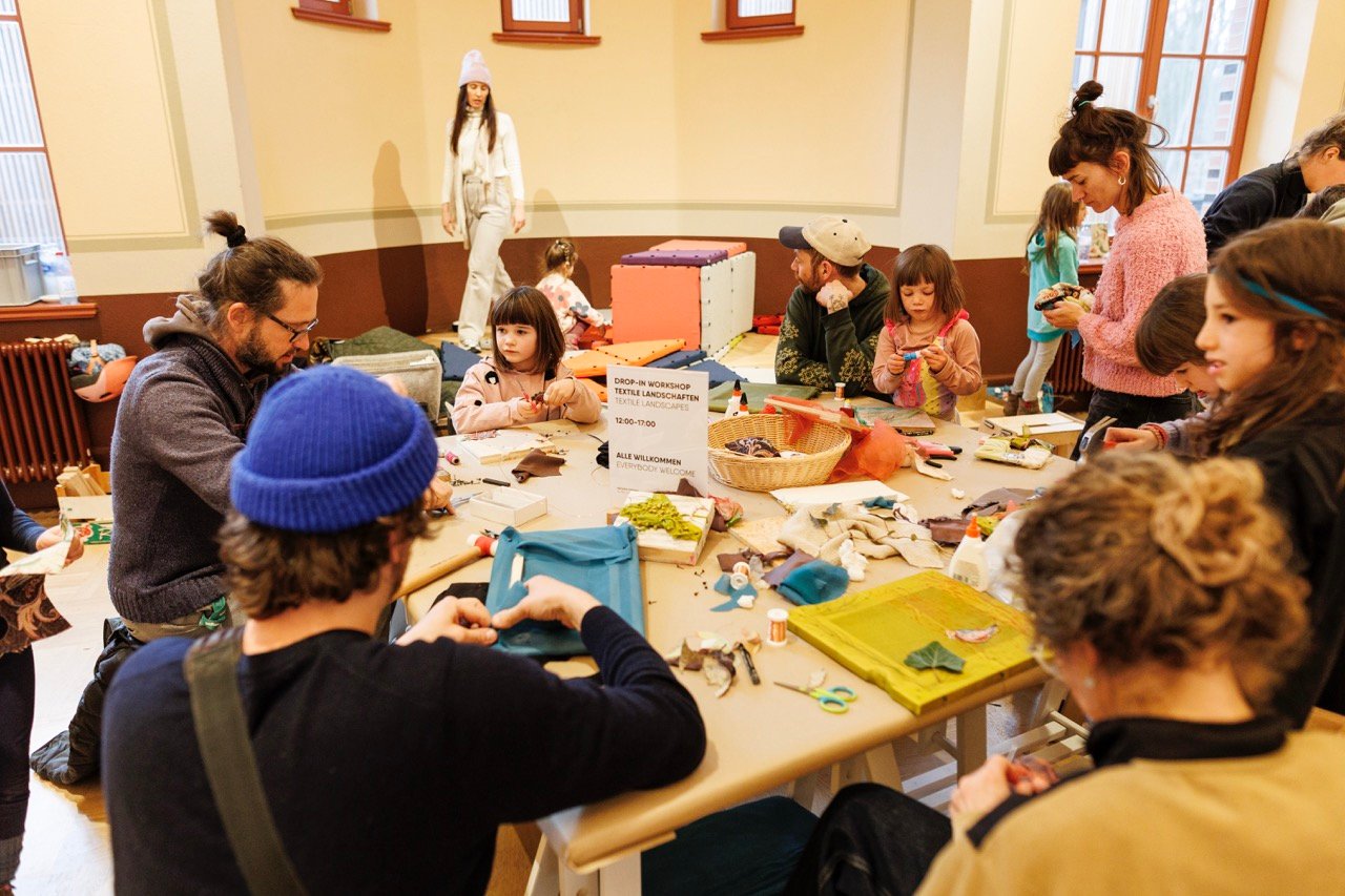Children and families gathered around a table at a drop-in workshop